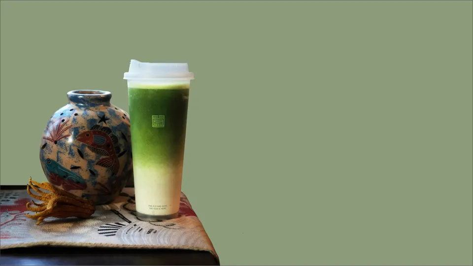 Gradient matcha latte beside a ceramic vase